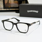 Black eyeglass frames with clear lenses, gold temple accents and small front emblem