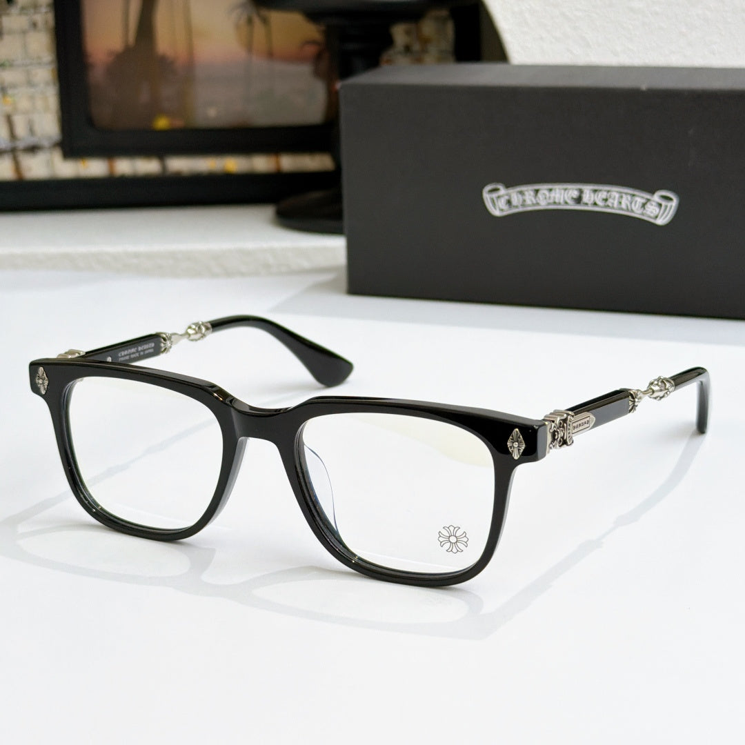 Black eyeglass frames with clear lenses, gold temple accents and small front emblem