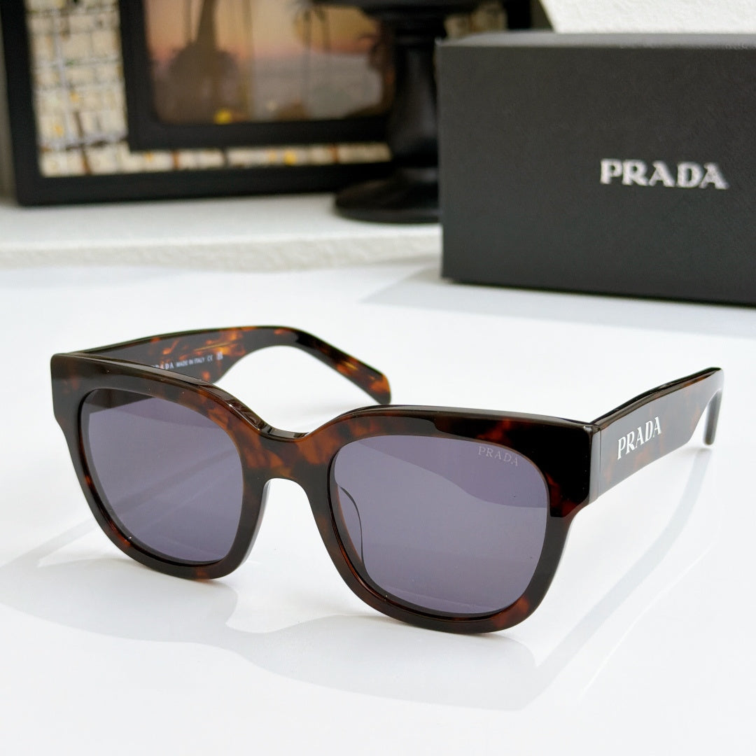 Tortoiseshell sunglasses with dark purple lenses and PRADA branding on temples