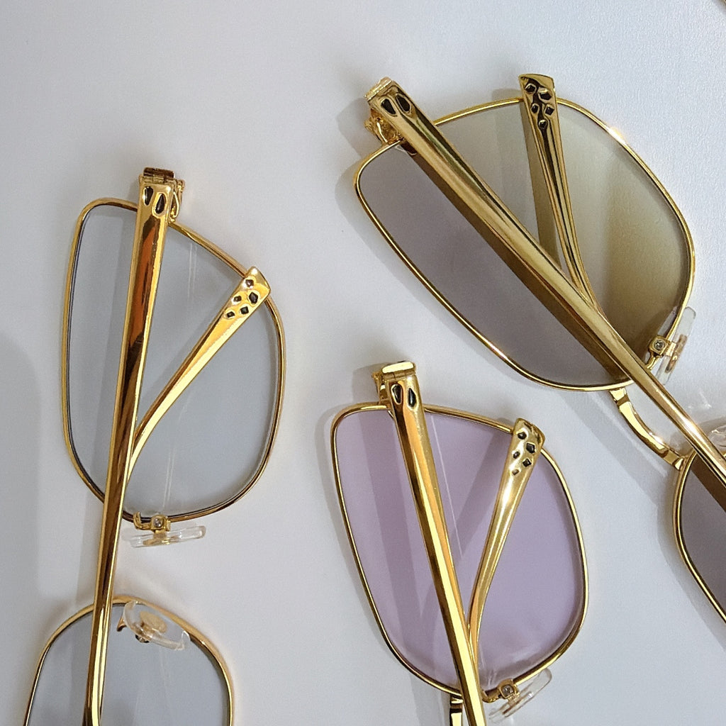 Gold-tone eyeglasses frames with pink-tinted lenses and textured side detail
