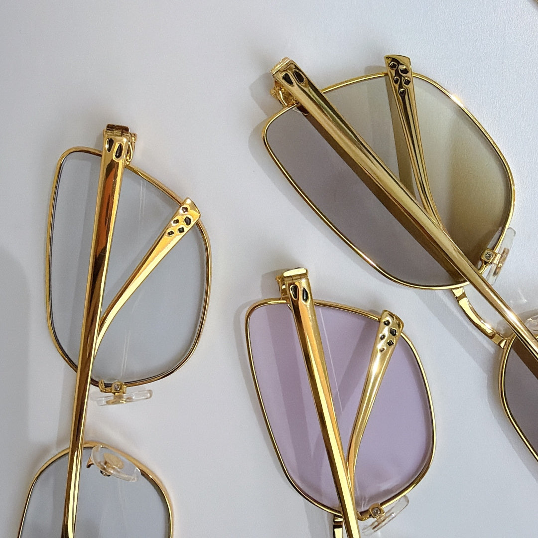 Gold-tone eyeglasses frames with pink-tinted lenses and textured side detail
