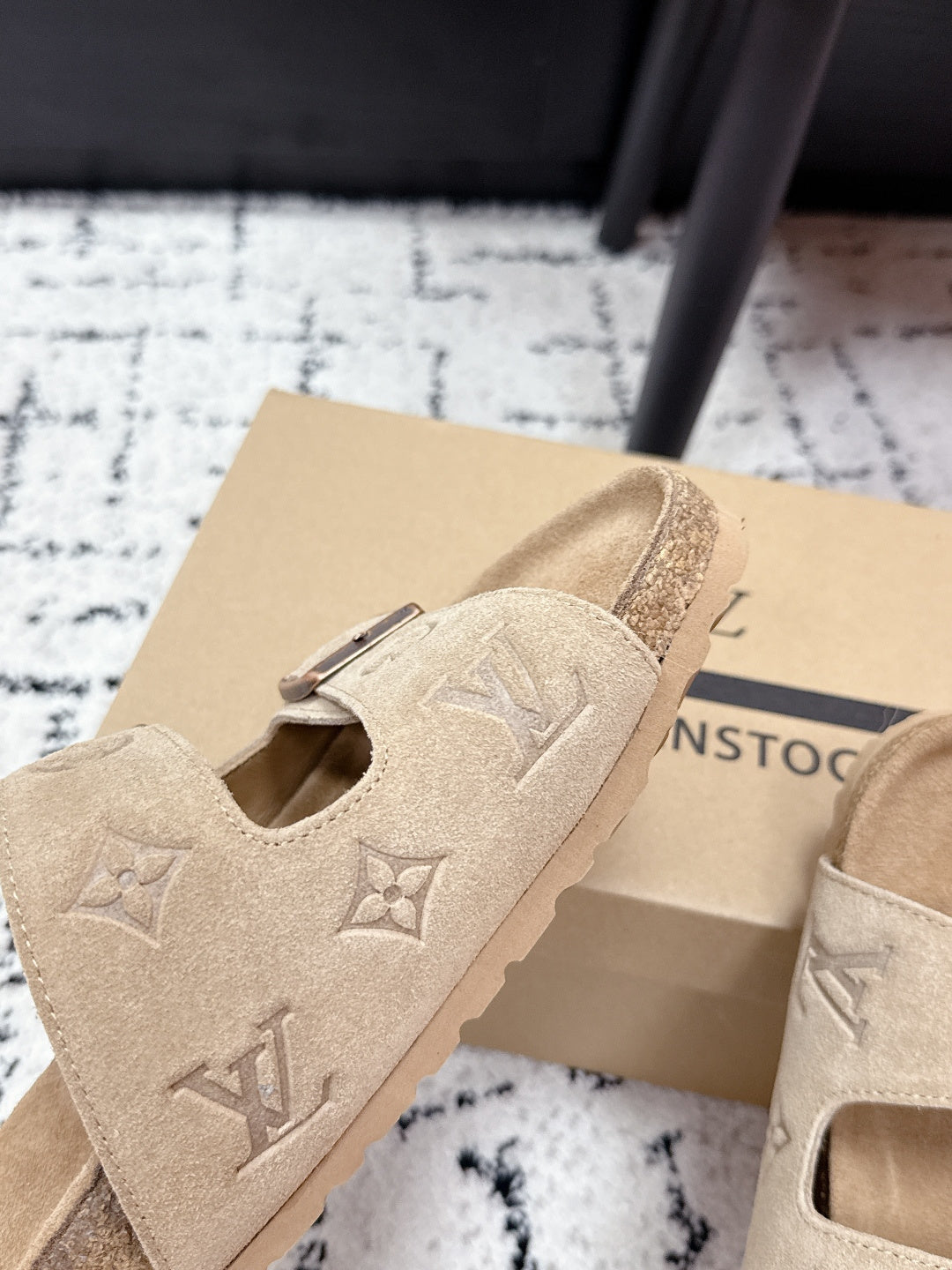Beige Louis Vuitton slide sandals close-up with logo-printed strap and buckle.
