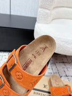 Orange slide sandal with single strap, silver buckle, and tan suede footbed