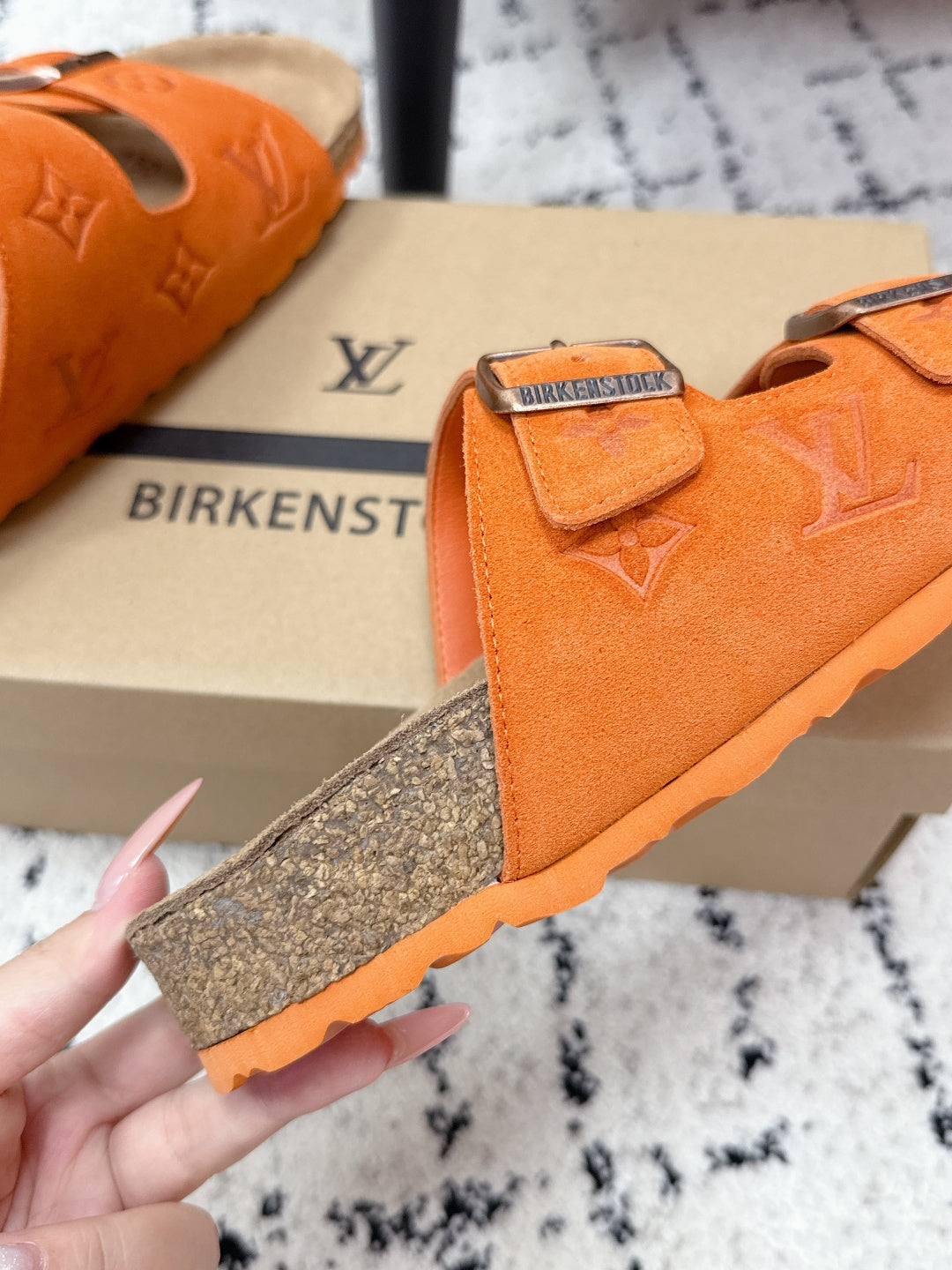 Orange sandal with textured sole and two silver-buckled straps