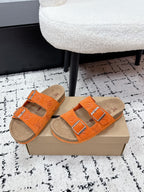 Pair of orange slide sandals with patterned straps and silver buckle details