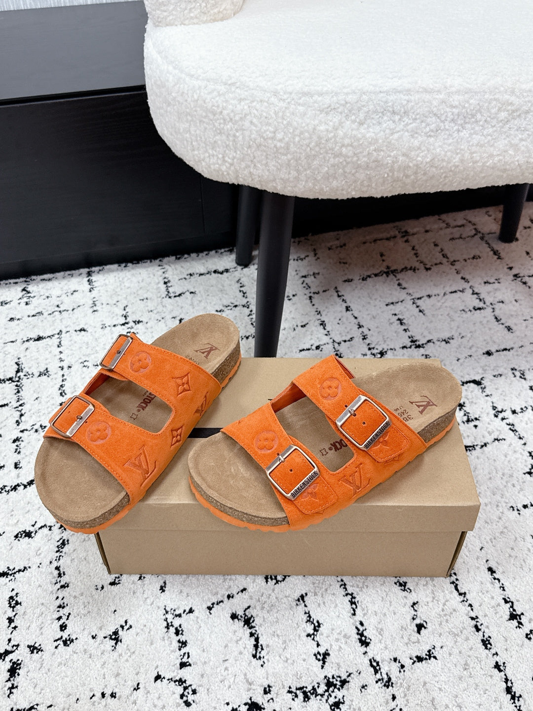 Pair of orange slide sandals with patterned straps and silver buckle details