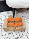 Orange slide sandals with double straps and silver buckles on tan footbed