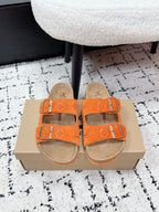 Orange slide sandals with double straps and silver buckles on tan footbed