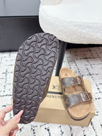 Louis Vuitton monogram slide sandals, patterned underside and tan strap detail.