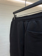 Dark shorts with elastic waistband, front pocket, and drawcord detail