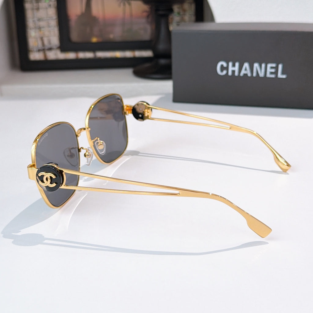 Side view gold-frame sunglasses with dark lenses and logo-style temple detail