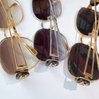 Gold-frame sunglasses cluster with dark lenses and metal temple hardware details