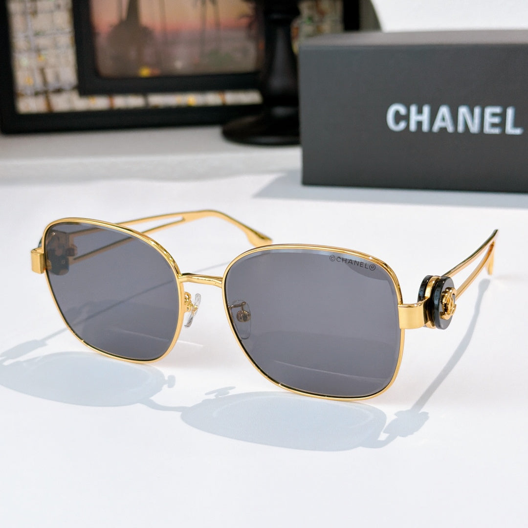 Gold-frame sunglasses with cool gray tinted lenses and bold rounded lenses