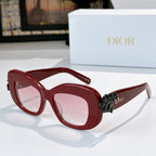 Dior sunglasses with red frames, pink-tinted lenses, and black floral temple embellishment
