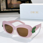 Dior sunglasses with pink frames, brown-tinted lenses, and green floral temple decoration