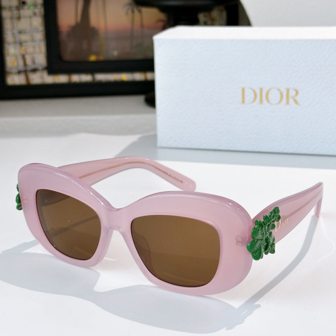 Dior sunglasses with pink frames, brown-tinted lenses, and green floral temple decoration
