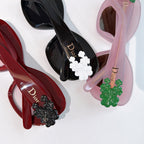 Dior sunglasses close view: red and pink frames with floral temple charms and tinted lenses