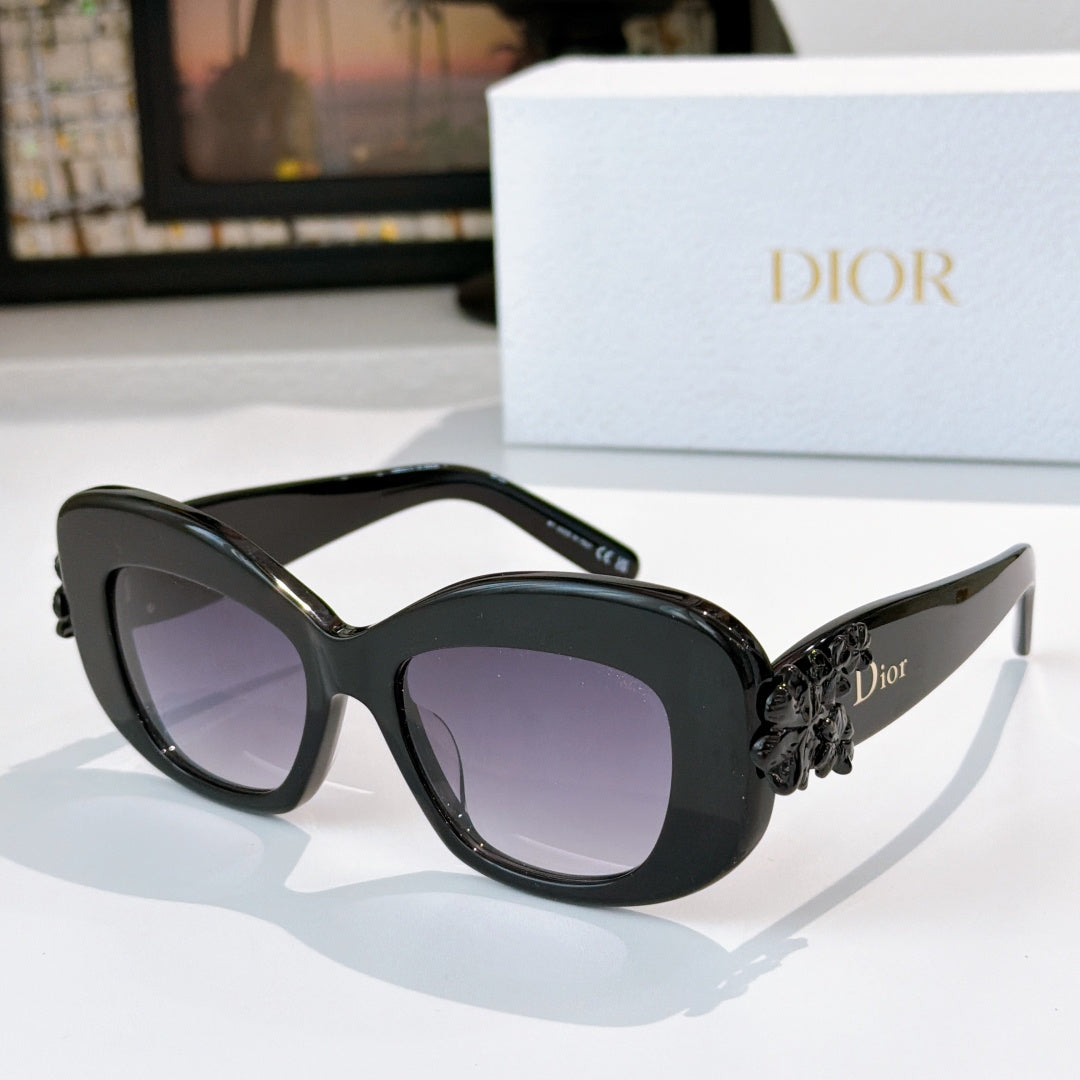 Dior sunglasses with dark frames, purple tinted lenses, and ornate floral temple embellishment