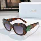 Dior sunglasses with tortoiseshell frames, dark lenses, and green floral temple detail