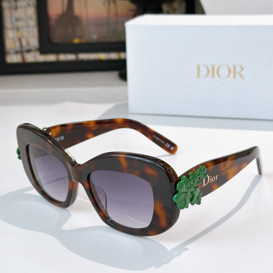 Dior sunglasses with tortoiseshell frames, dark lenses, and green floral temple detail