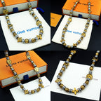 Louis Vuitton beaded necklace with gold and silver charms shown on box and pouch