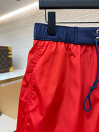 Red swim shorts with navy waistband and drawstring loops, side close-up
