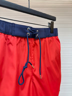 Red swim shorts waist close-up with navy drawstring and eyelets, hanging