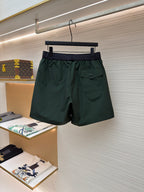 Green shorts with drawstring waist, dark waistband, and side pocket flap details