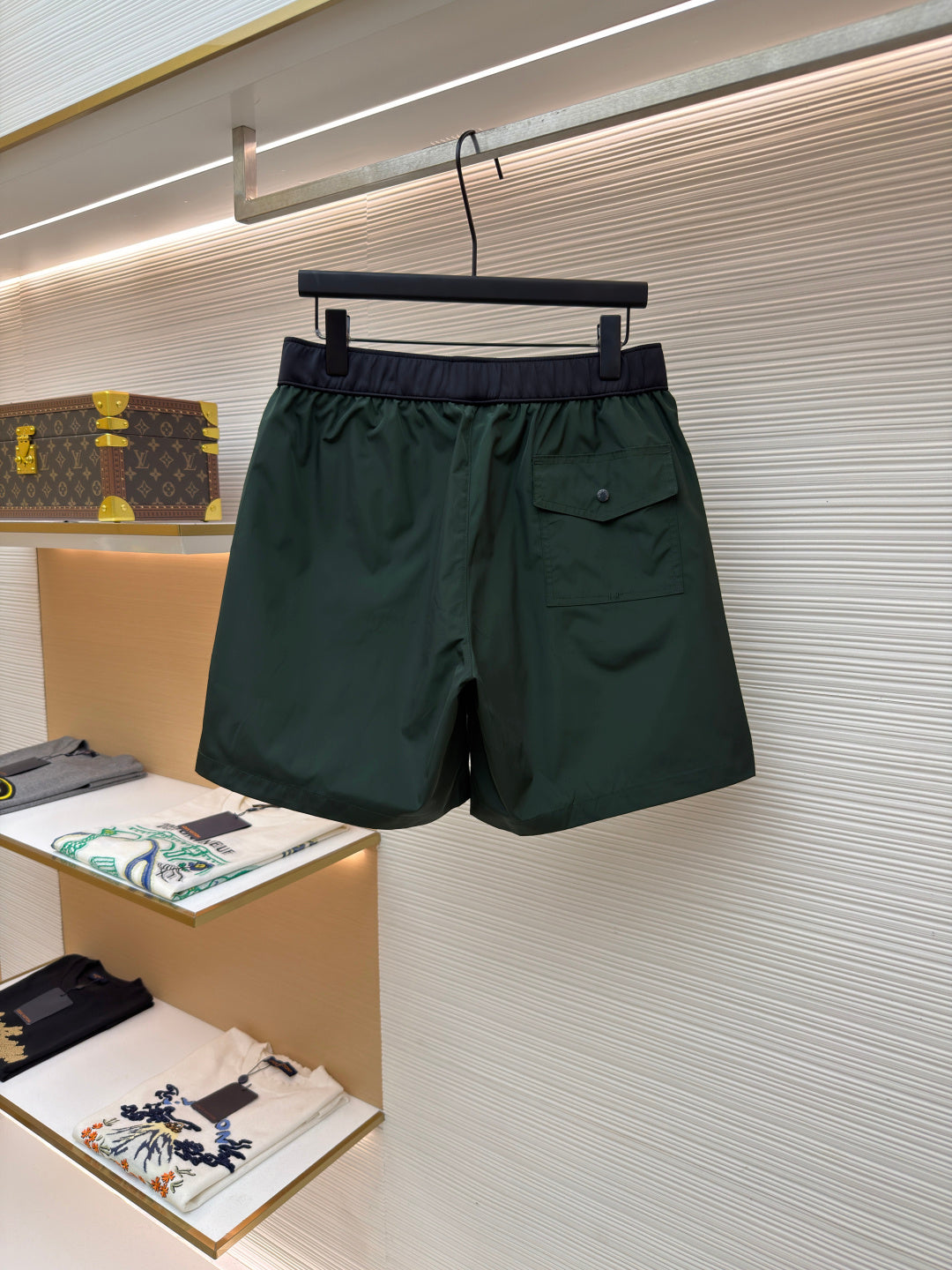 Green shorts with drawstring waist, dark waistband, and side pocket flap details