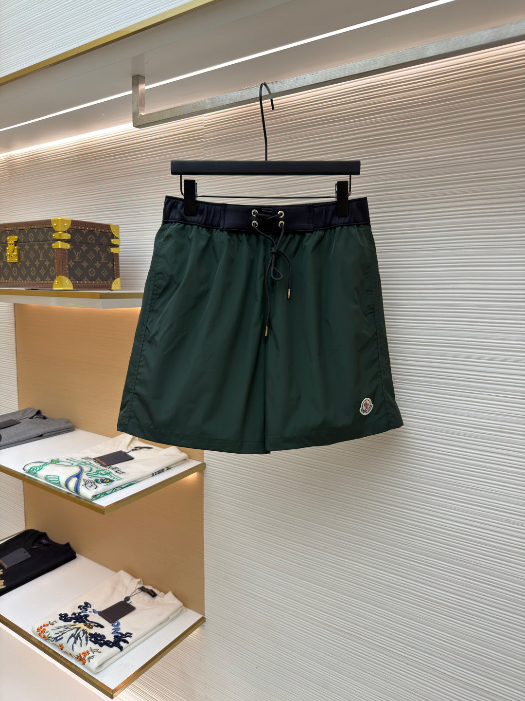 Green drawstring shorts with elastic waistband and front pockets, hanging on a rack