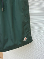 Green shorts with small circular logo patch on the lower front hem