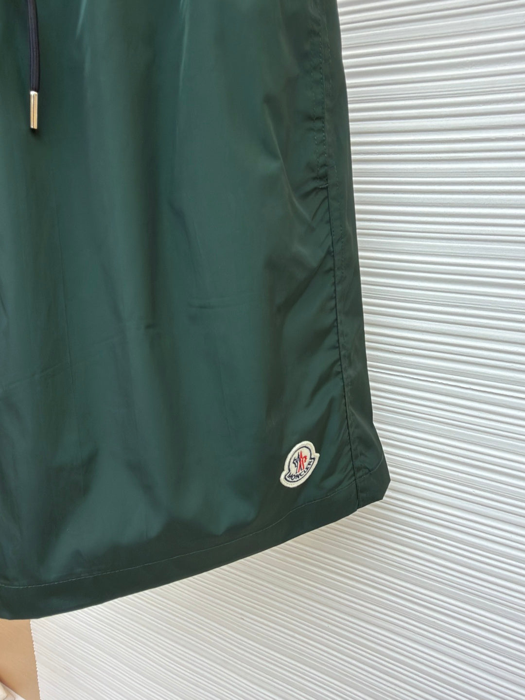 Green shorts with small circular logo patch on the lower front hem