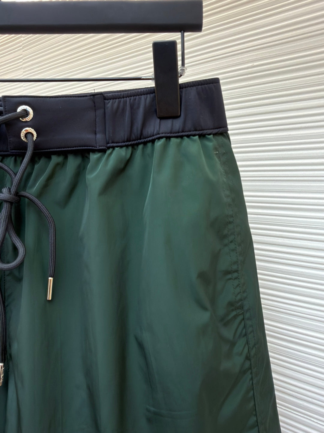 Green shorts with drawstring cord and zipperless front, dark waistband trim