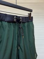 Green drawstring shorts with lace-up cords and grommet accents at the waistband