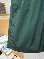 Green shorts with curved back yoke seam and smooth fabric, shown hanging