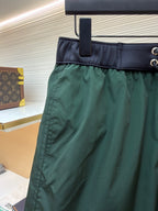 Green shorts with dark waistband band and side seam pocket detail, on a hanger
