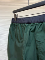 Green shorts with front pleats and right side pocket opening, hanging on a rack