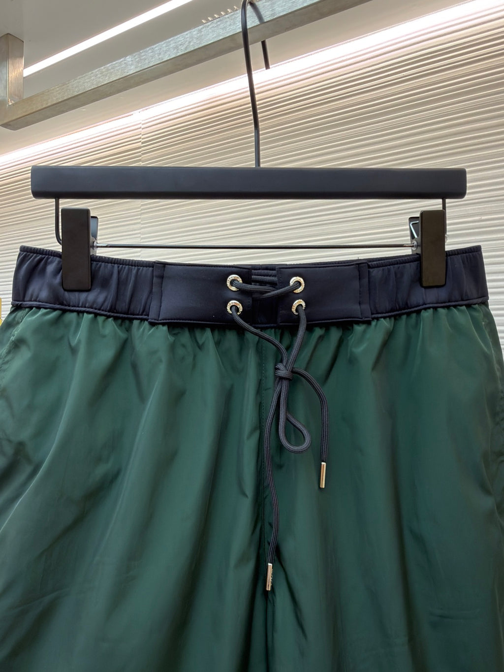 Close-up of green drawstring shorts waistband with metal eyelets and cord ties