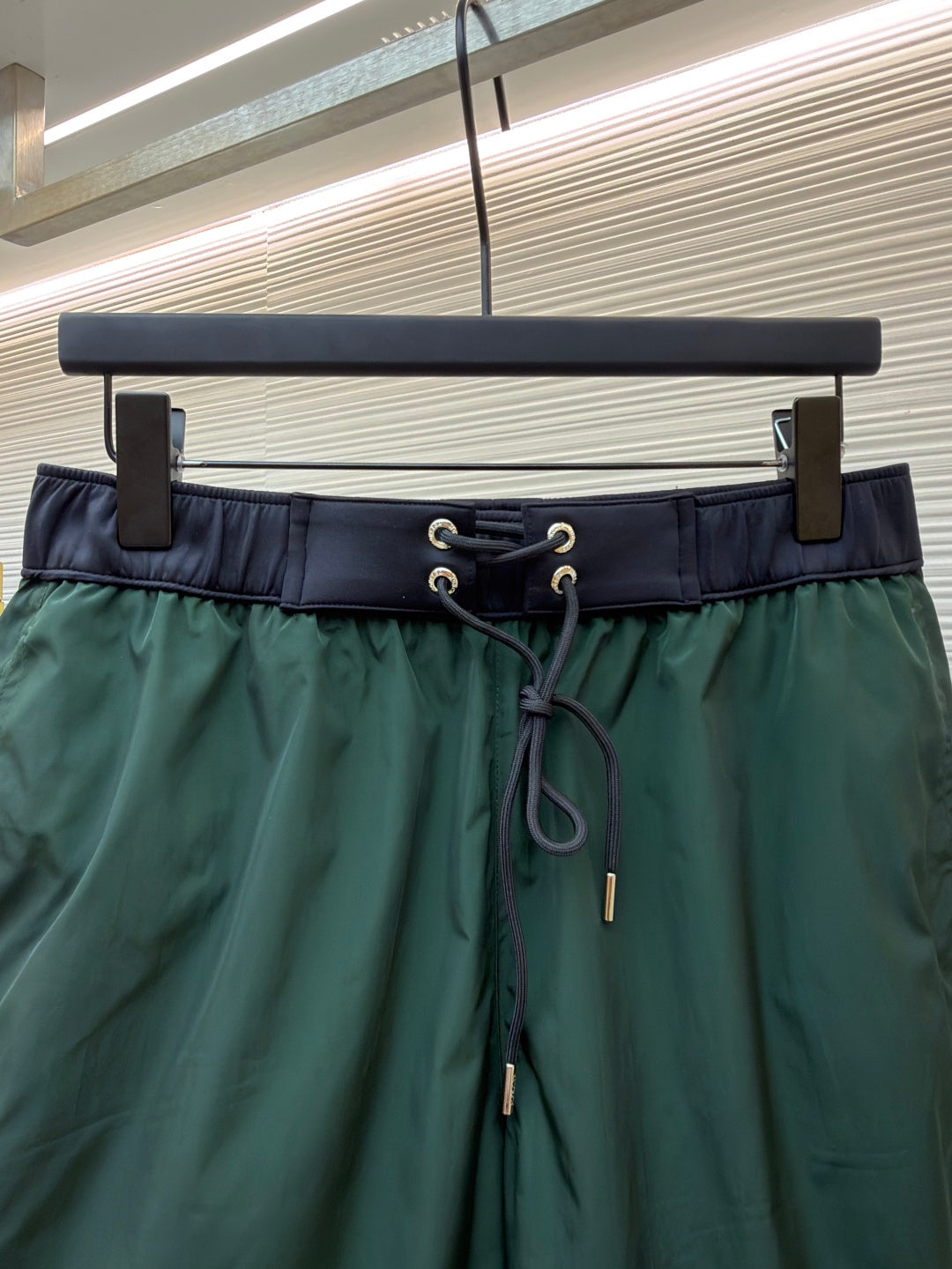 Close-up of green drawstring shorts waistband with metal eyelets and cord ties