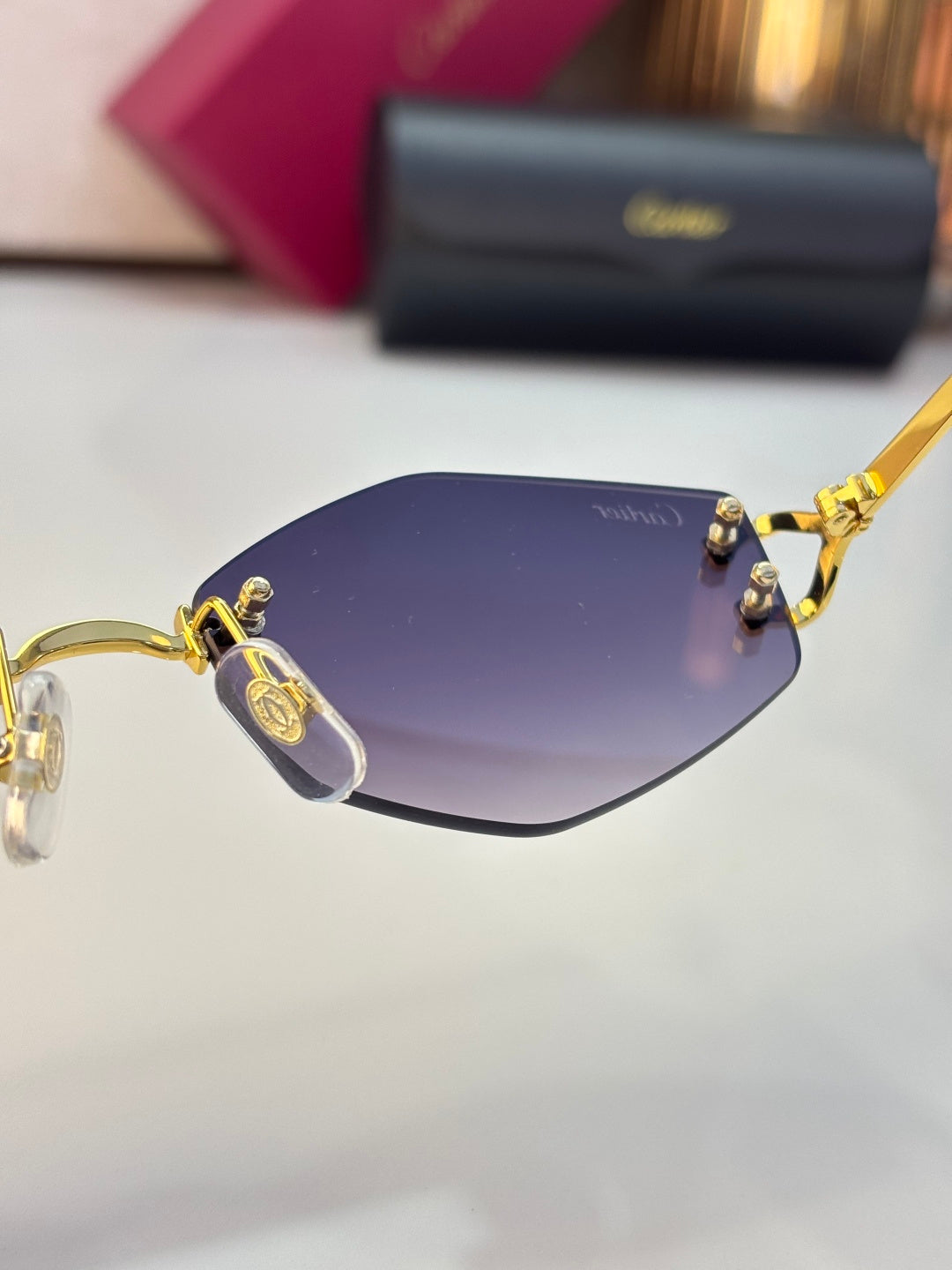 Close-up of gold sunglasses frame with purple tinted lenses and logo details