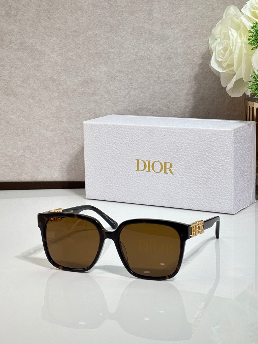 Black sunglasses with gold logo hardware and brown-tinted lenses