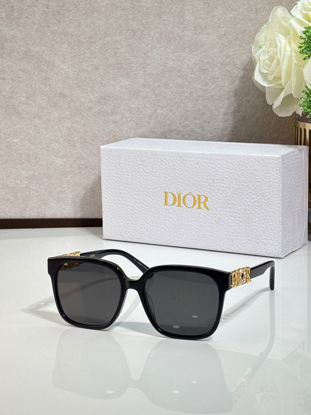 Black sunglasses with gold logo hardware and dark lenses
