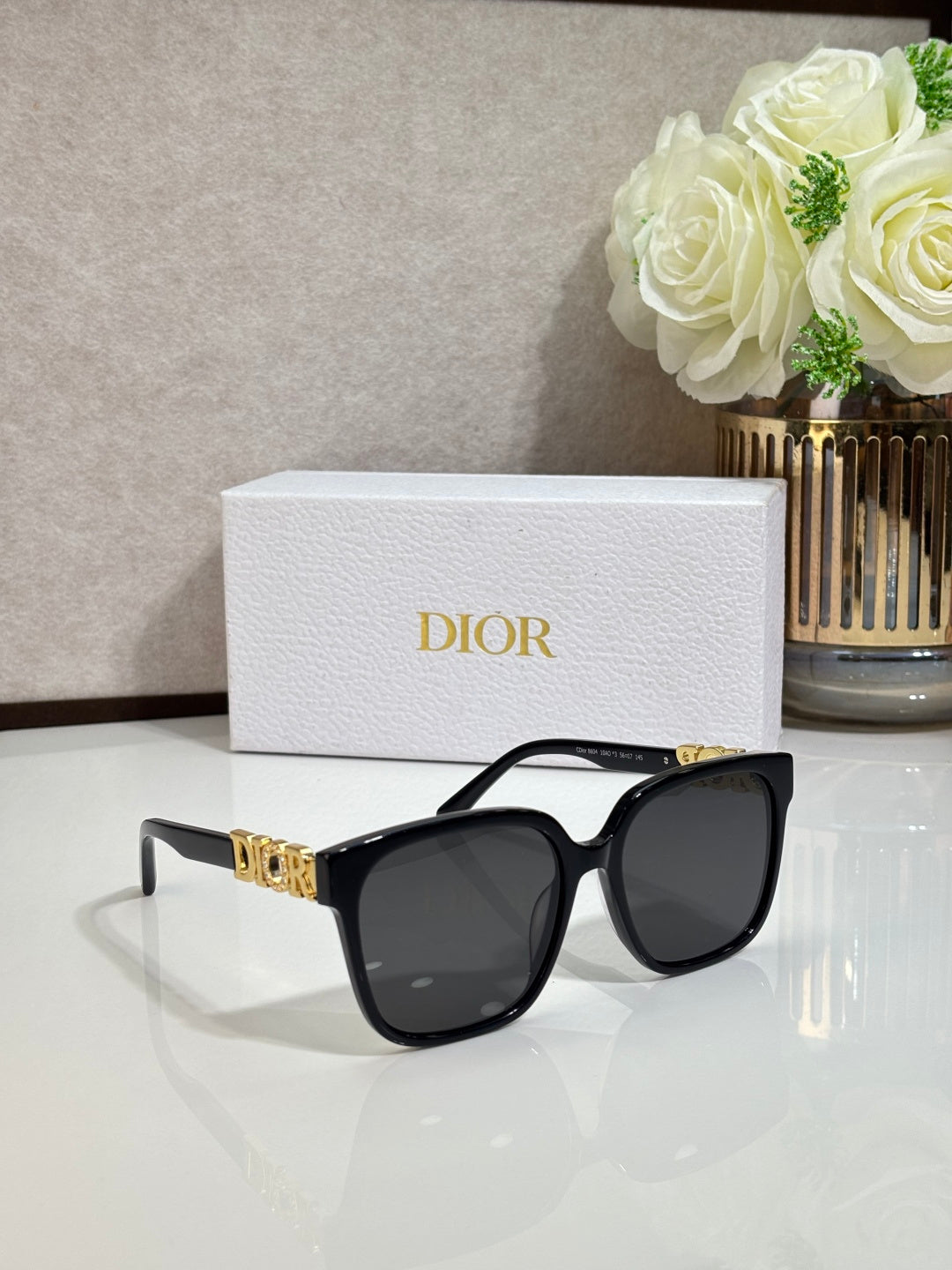 Black sunglasses with gold logo detail and dark lenses