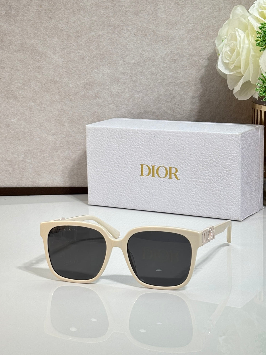 Cream sunglasses with gold logo hardware and dark lenses