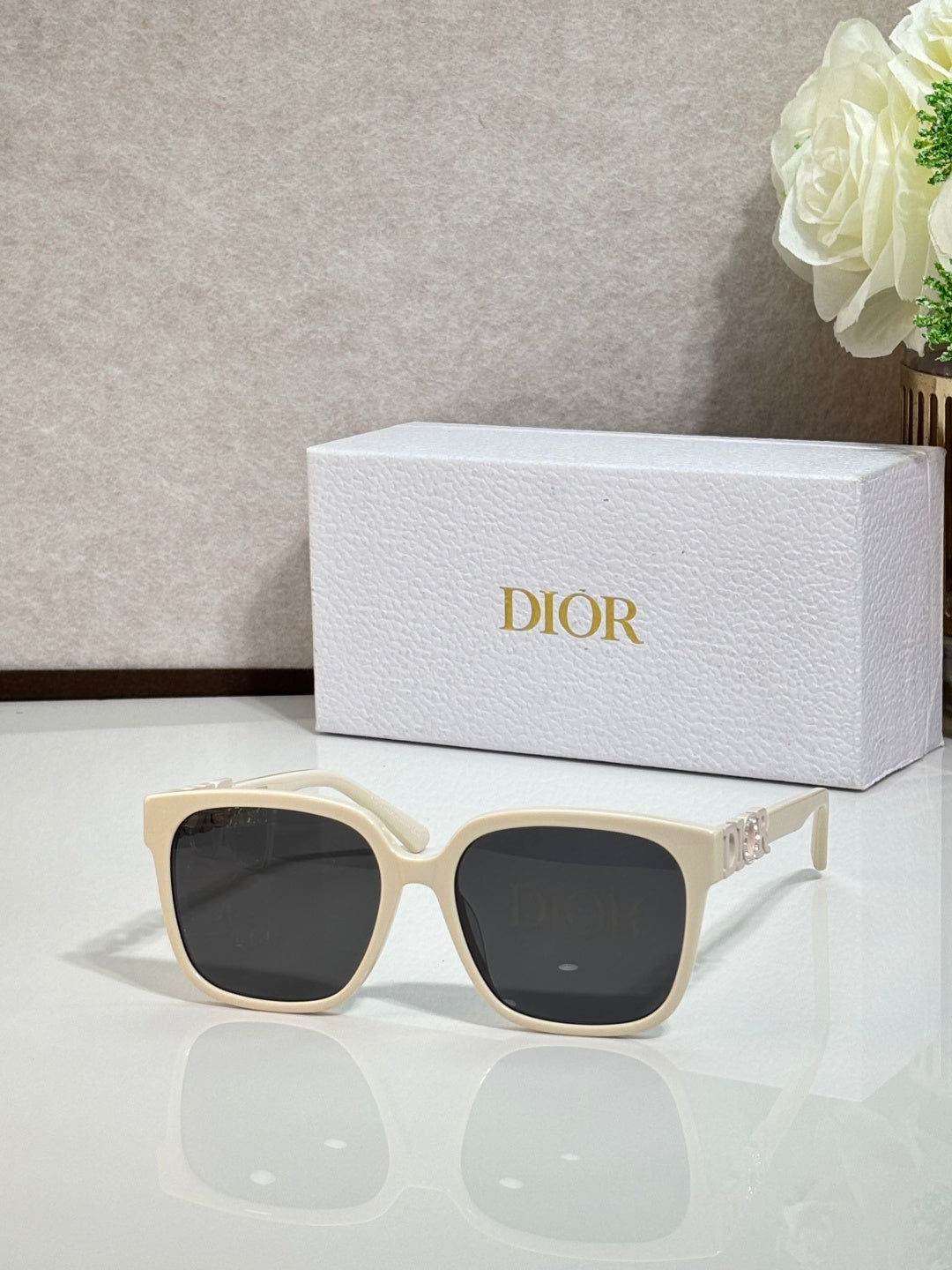 Cream sunglasses with gold logo hardware and dark lenses