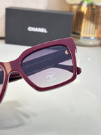 Sunglasses with maroon frames and tinted lenses, close-up