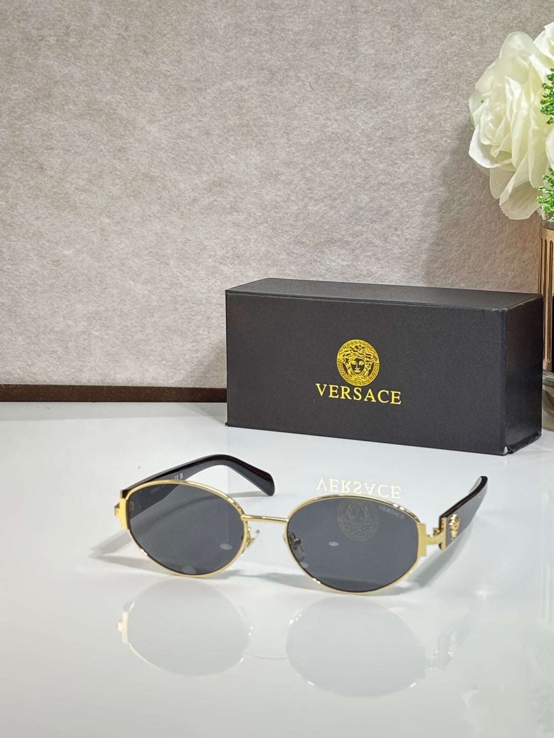 Round sunglasses with dark lenses, gold-tone frame, and black temple tips
