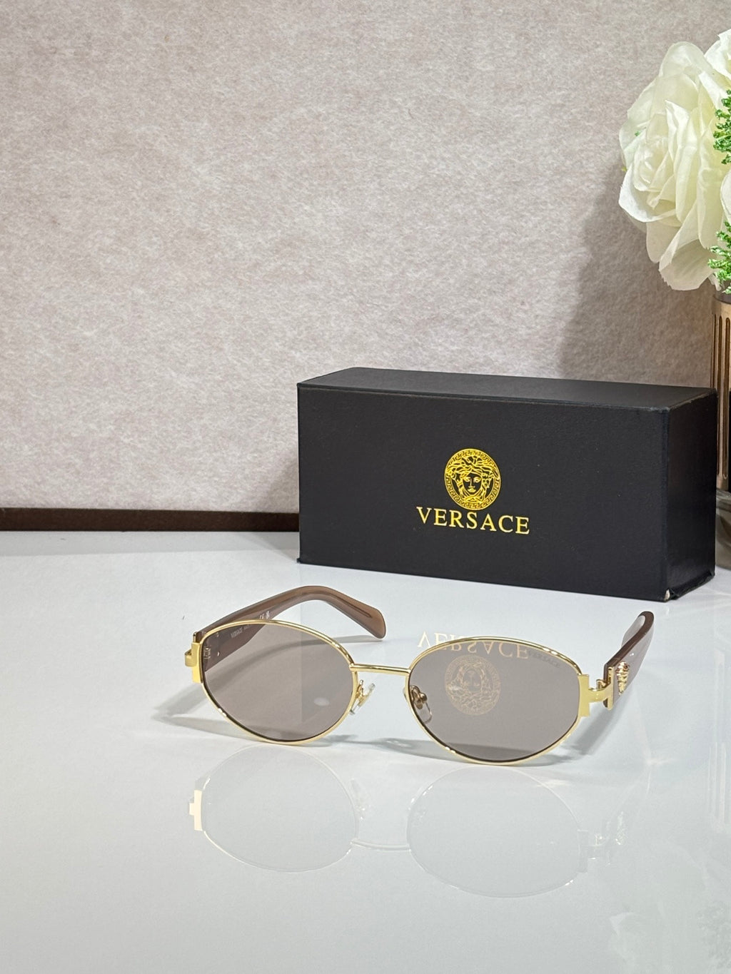 Round sunglasses with clear-smoke lenses, gold-tone frame, and black temple tips