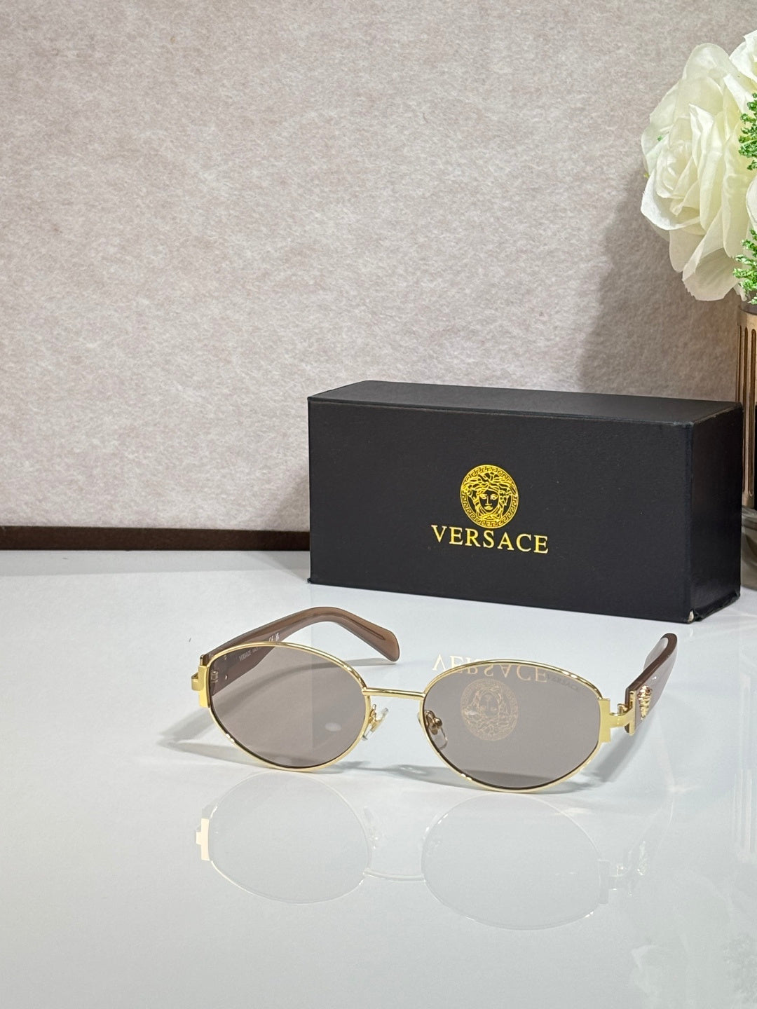 Round sunglasses with clear-smoke lenses, gold-tone frame, and black temple tips
