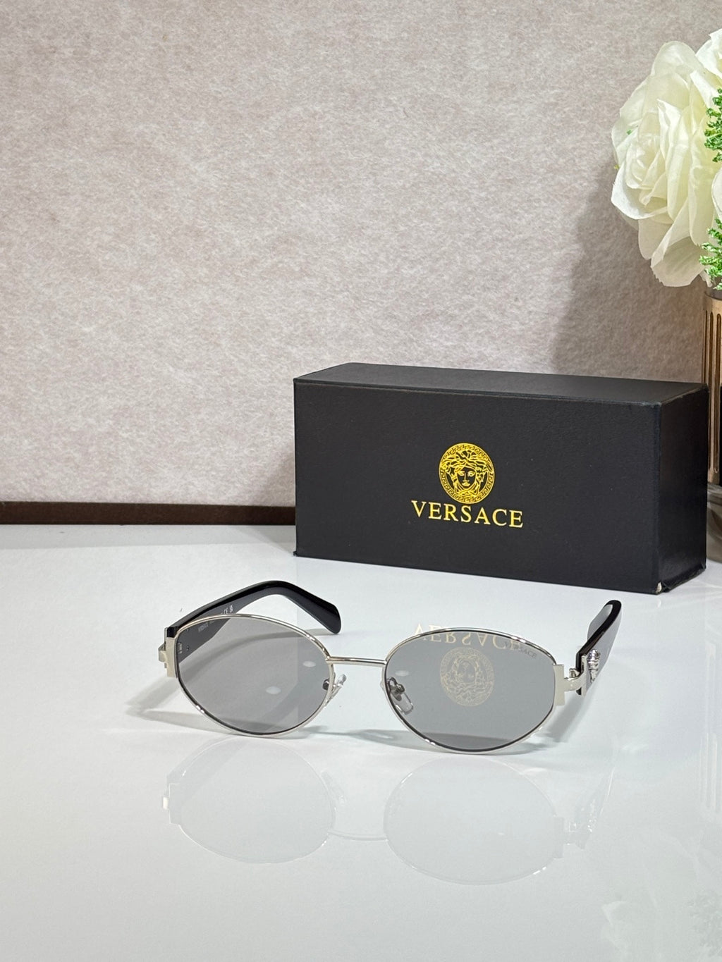 Round sunglasses with dark gray lenses, gold-tone frame, and green temple accents